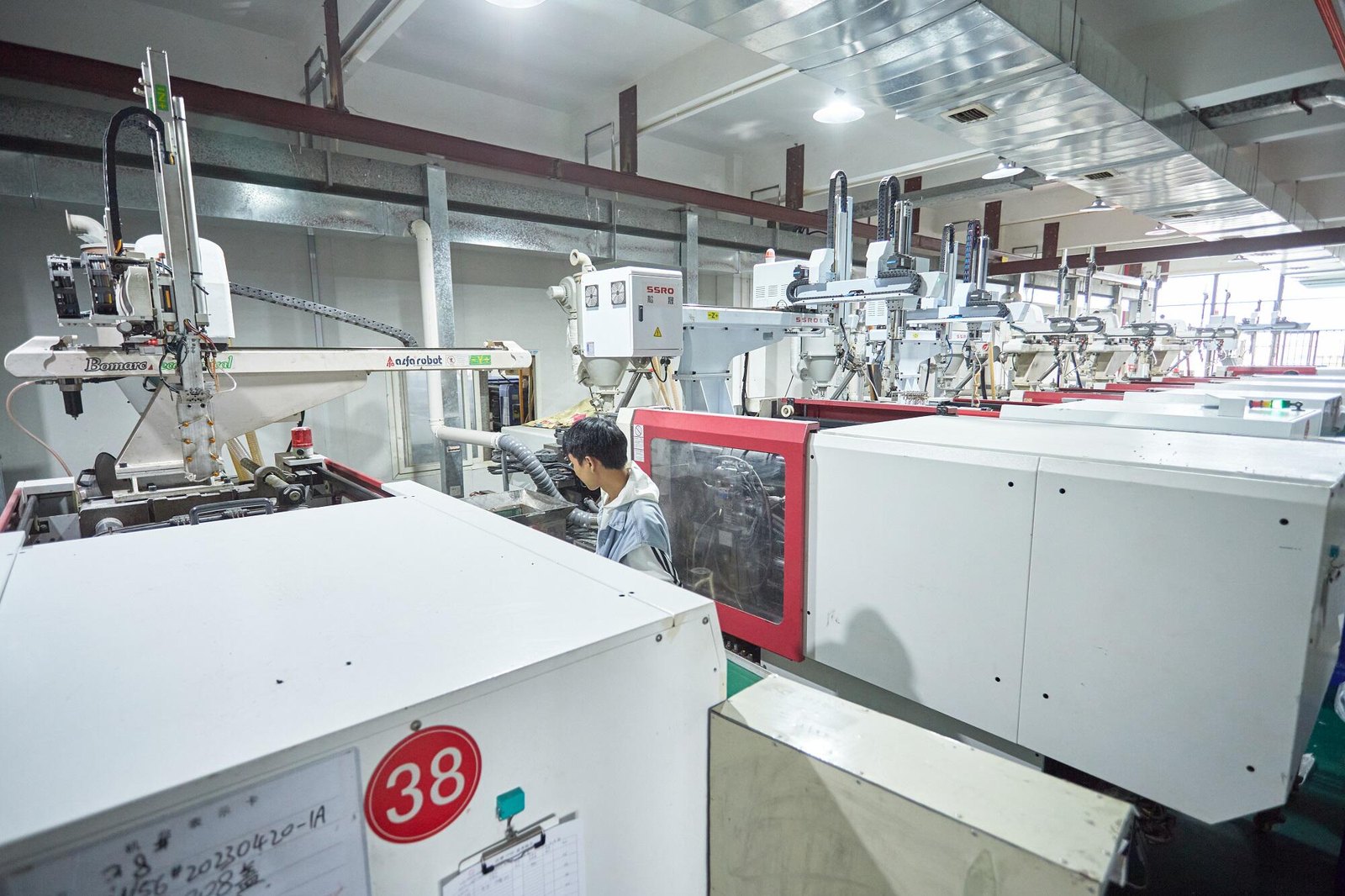 Injection moulding machine with robotic take-out arm on the moulding floor