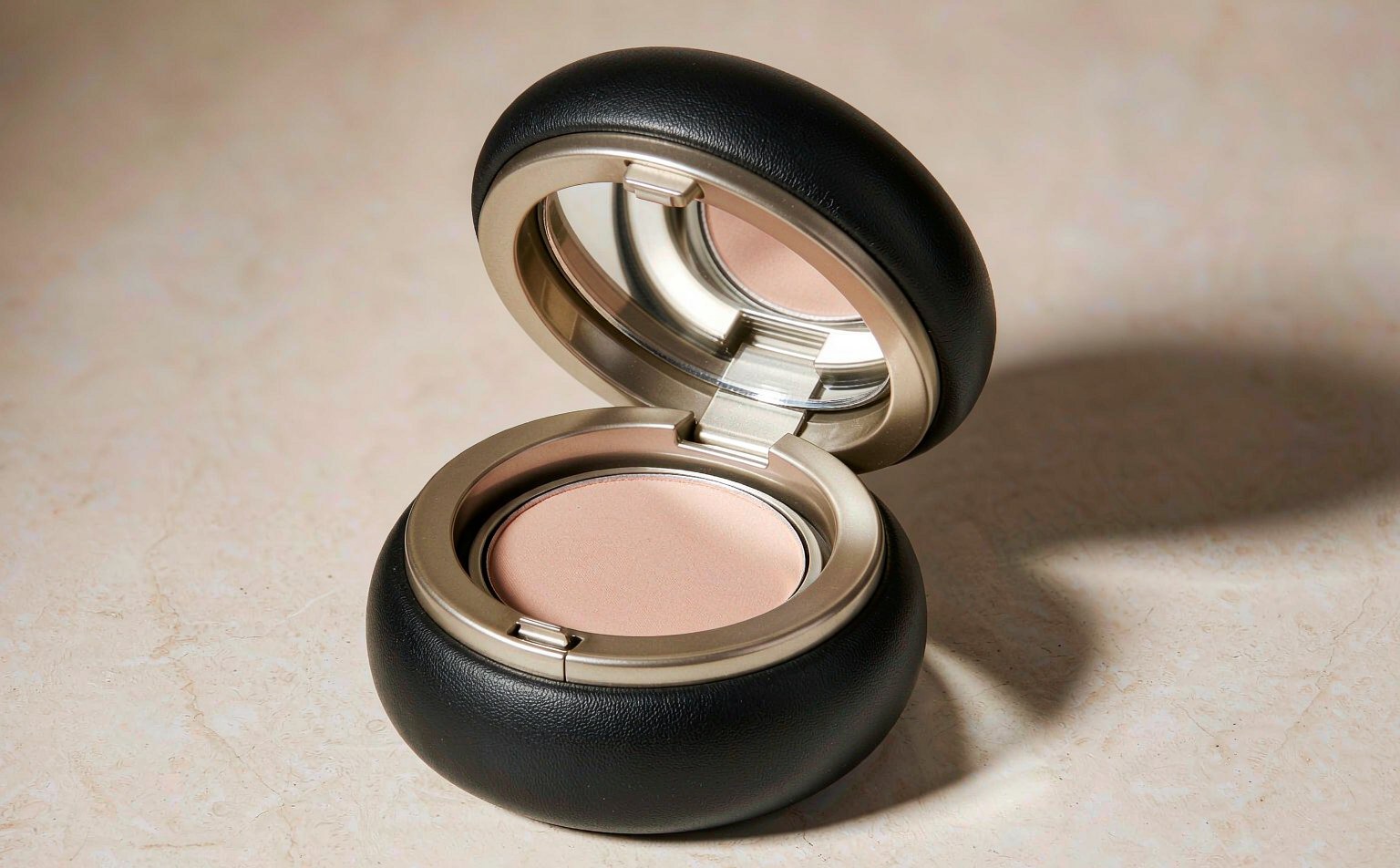 Luxury powder compact in matte black with champagne gold rim, opened